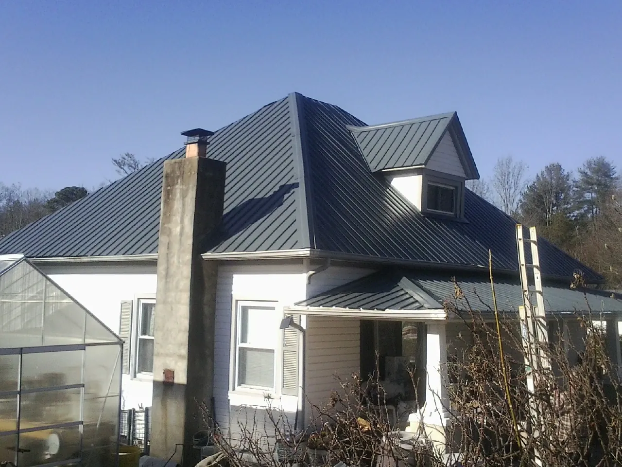 Dark blue standing seam metal roof on a white farmhouse with dormer — Slate & Tile Roof Repair by Roofing Brothers in Danube