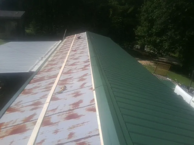 Old rusted panels beside newly installed green metal roofing — Wind Damage Roof Repair by Roofing Brothers in Danube