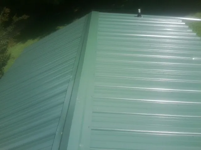 New green metal panels meeting at the ridge of a roof — Flat Roof Repair work by our crew in Danube