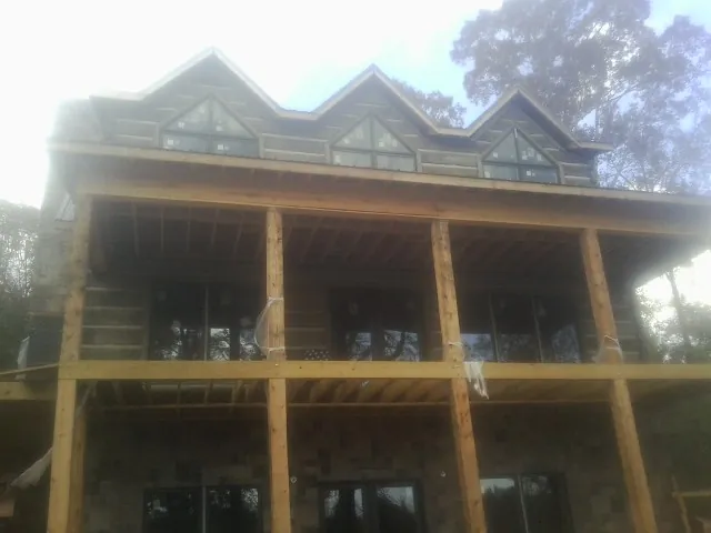 Dormers and porch framing on a large log home under construction — Roof Coating work by our crew in Danube