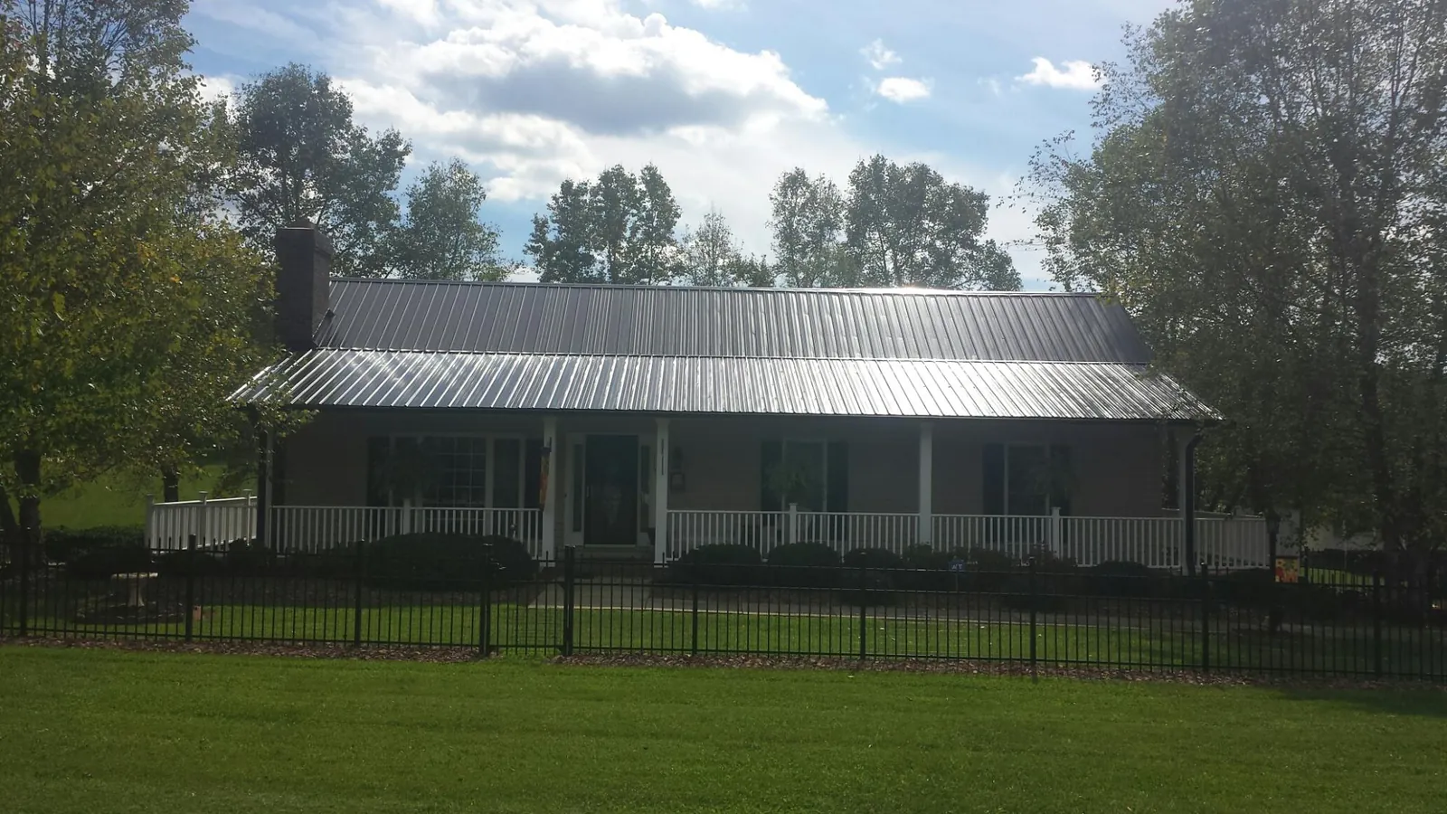 Gray metal roof on a brick ranch with a full width front porch — Gutter Guard Installation work by our crew in Danube