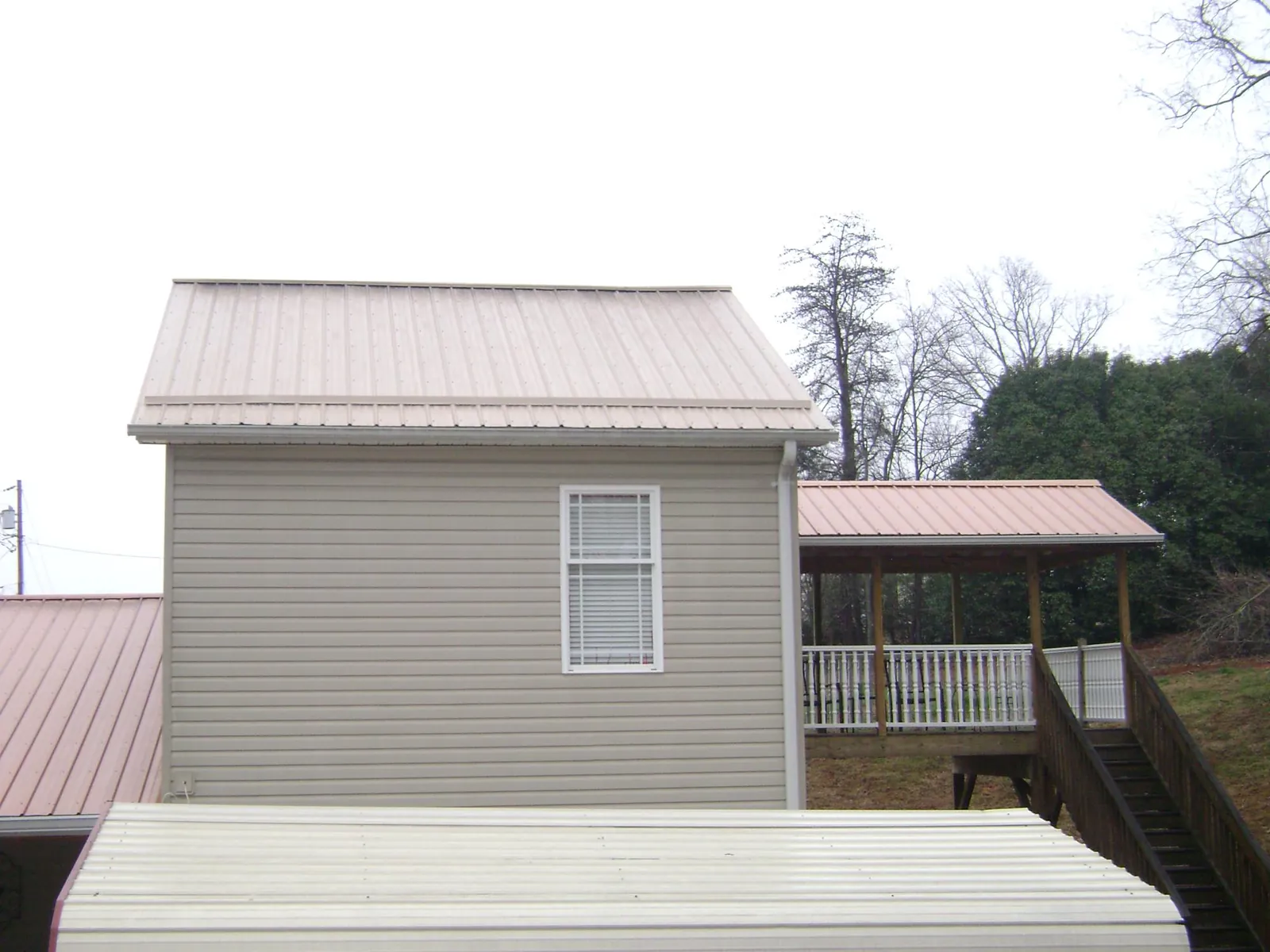 Tan metal roofs on a two story addition and attached porch, from a Roof Replacement job in Danube