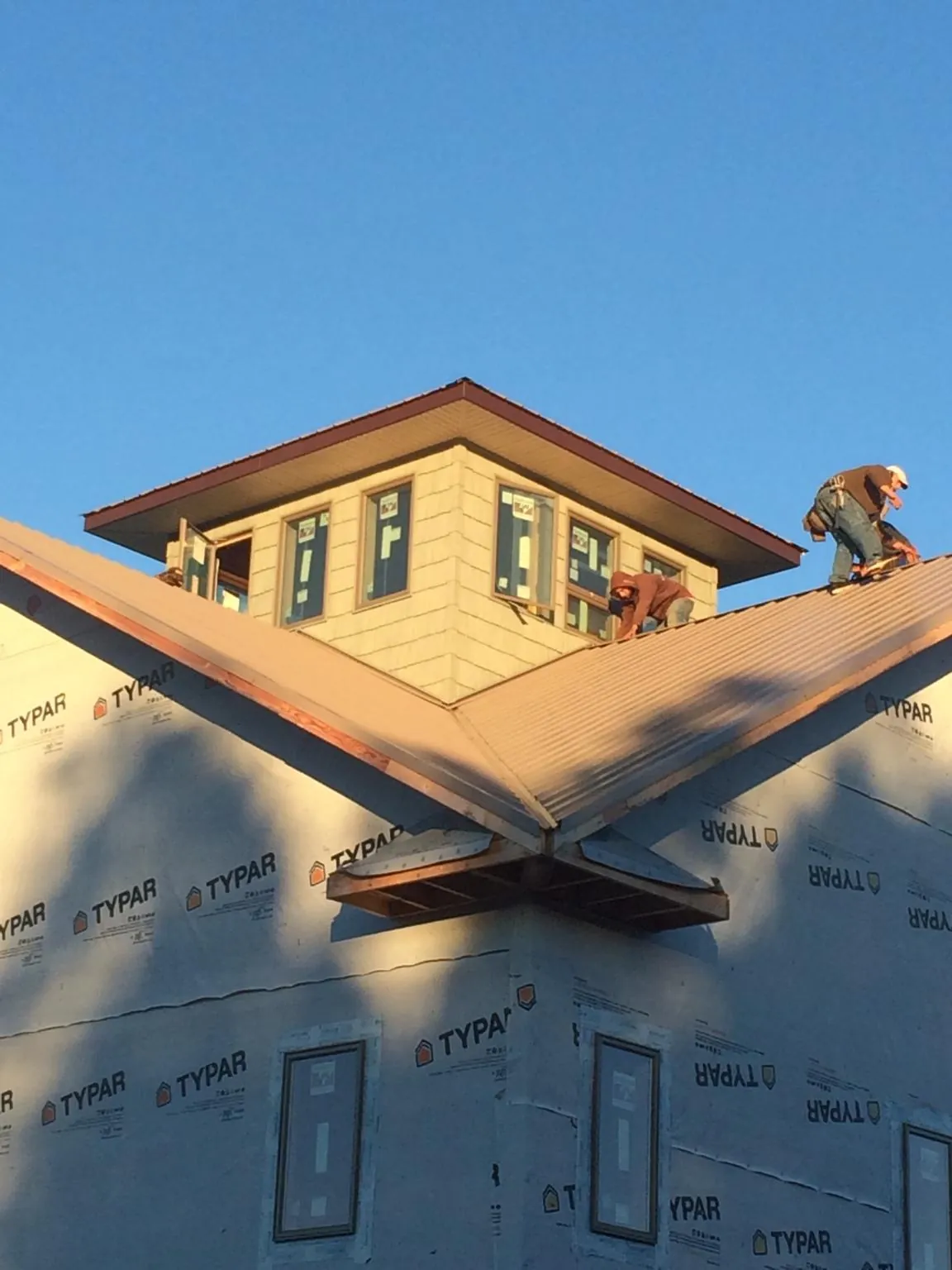 Roofers working around a rooftop cupola on a new metal roof at sunset — Roof Waterproofing in Danube by Roofing Brothers